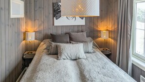 A bedroom with a large bed, two bedside lamps, a framed artwork above the bed, and a window with curtains. - Herlig ferie nær Møsvatn (Rjukan)