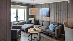 A modern living room with a grey sectional sofa, a round coffee table, and a hanging light fixture. - Herlig ferie nær Møsvatn (Rjukan)