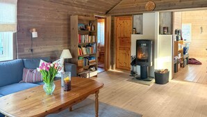 Una sala de estar acogedora con un sofá, una mesa de centro de madera, una estantería, una chimenea y una puerta que da a otra habitación.