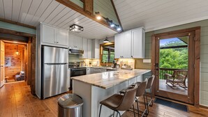 Een moderne keuken met witte kasten, roestvrijstalen apparatuur en een houten kookeiland met barkrukken.