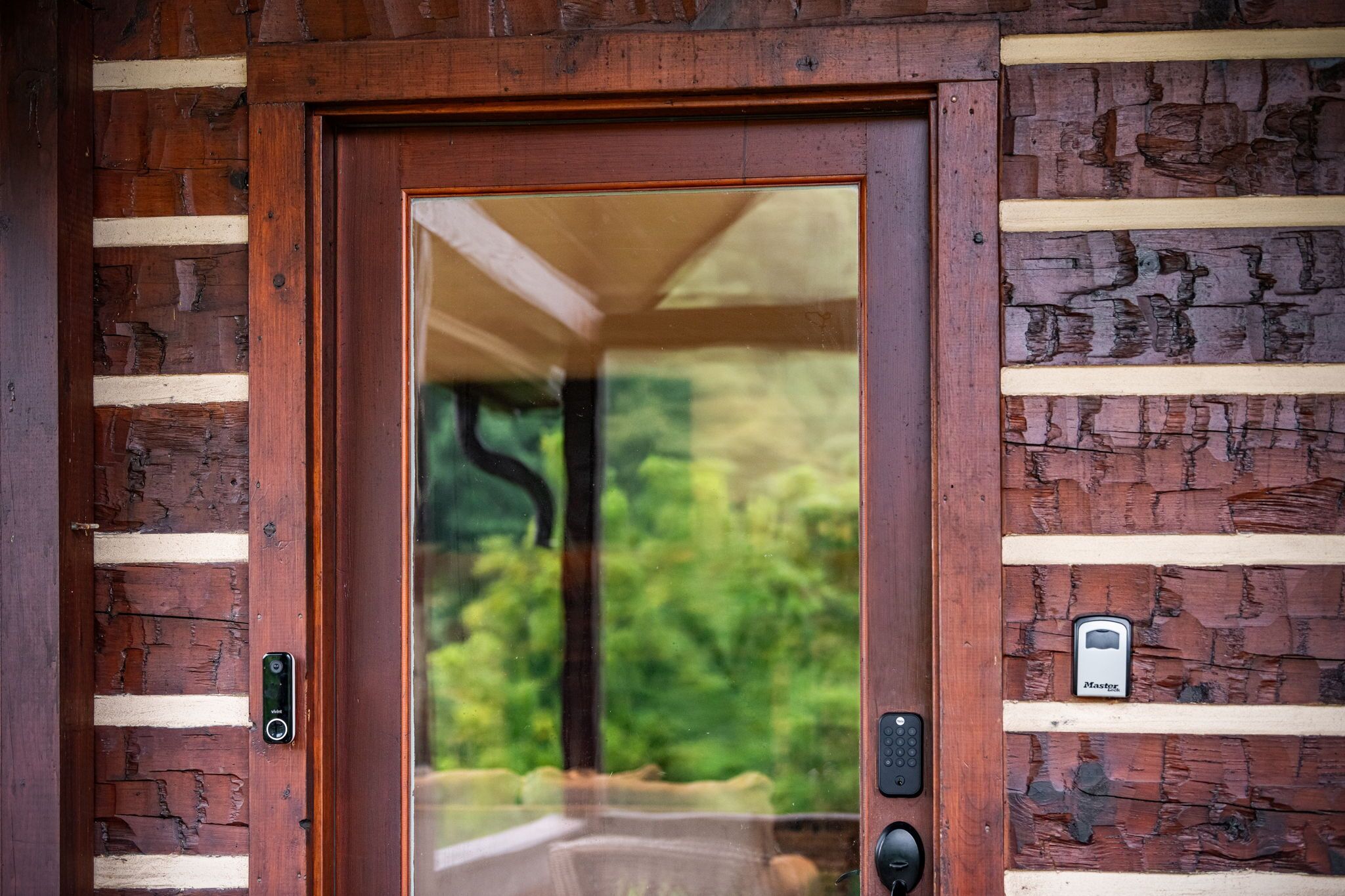 A wooden door with a keypad lock and a small electronic device on the wall beside it.