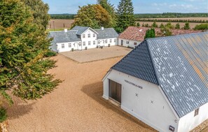 A large white building with a grey roof, surrounded by a gravel driveway and trees. - 3 bedroom amazing home in Herning (Herning)