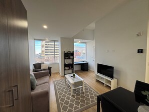 A modern living room with a sofa, coffee table, TV, and a bookshelf. - Cozy 2-bedroom condo in enchanting Edmonton with AC and gym access (Edmonton)