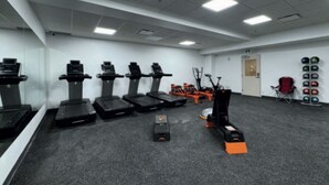Une salle de sport équipée de tapis de course, de vélos d’appartement et d’un appareil d’aviron.