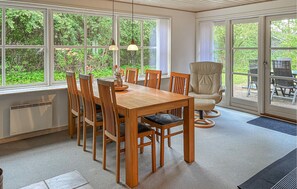 A dining area with a wooden table and chairs, large windows, and a view of greenery. - 2 bedroom lovely home in Toftlund (Toftlund)