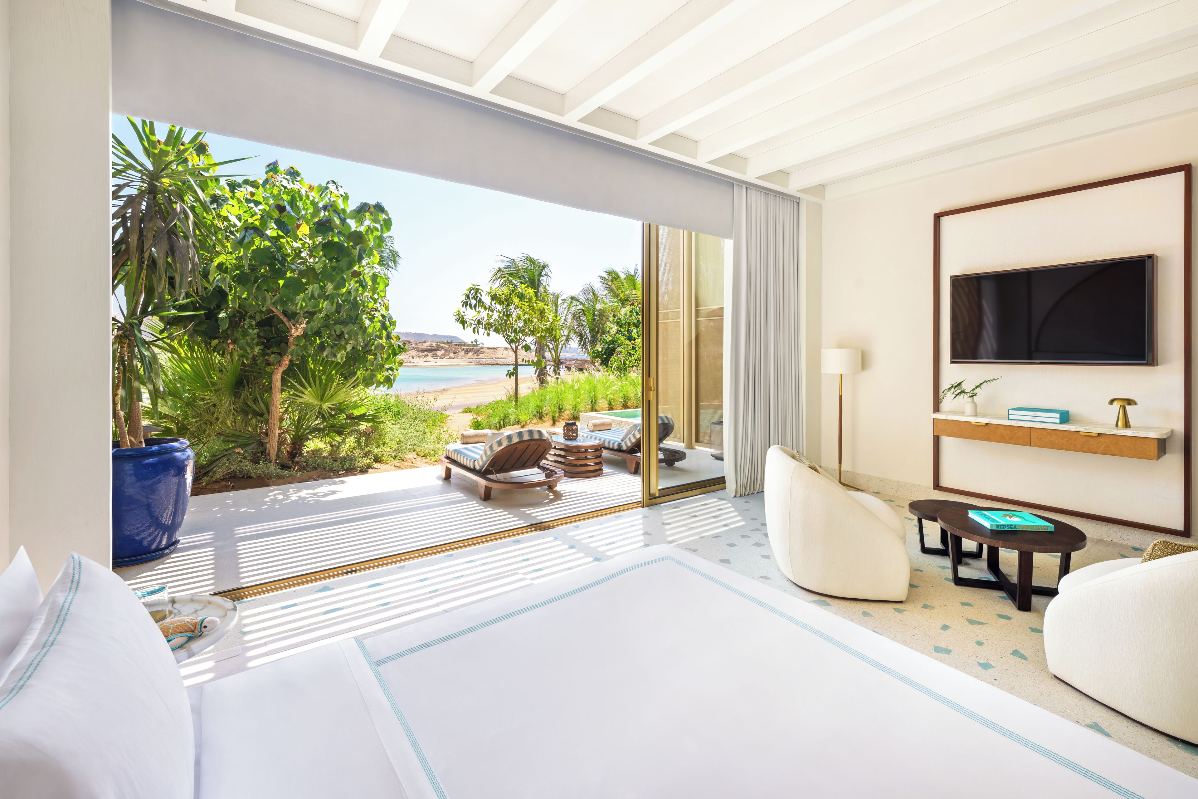 Una habitación de hotel con cama, televisión, sofá y vista al mar.