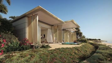 Uma casa moderna com um amplo pátio, piscina e vista para a praia.