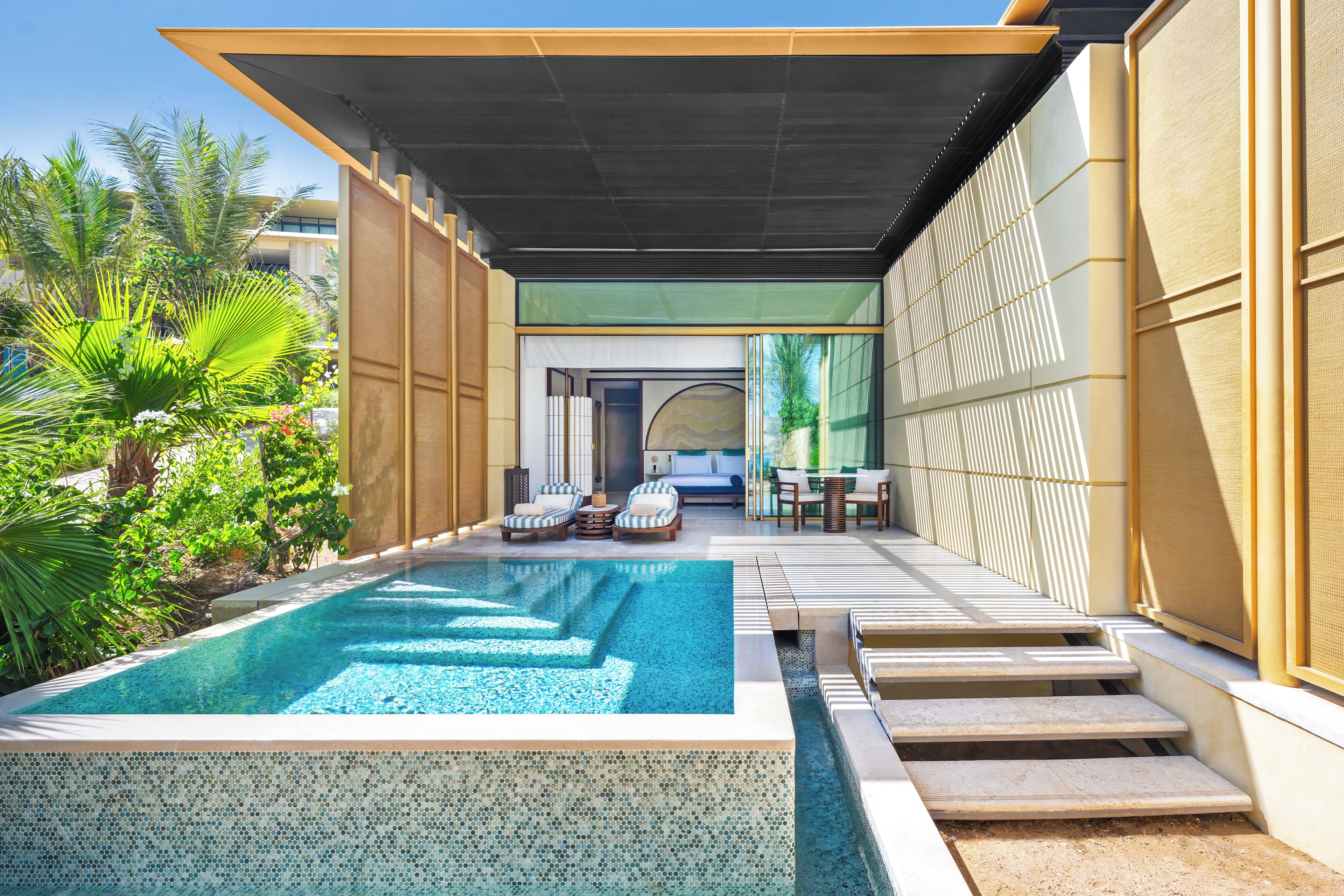 A swimming pool with lounge chairs and a covered seating area.