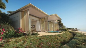 Een modern huis met twee verdiepingen, een zwembad, omringd door weelderige begroeiing en uitzicht op het strand.