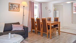 Un salon chaleureux avec un canapé, une table à manger et des chaises, une lampe et un tableau au mur.