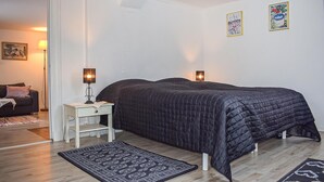 Une chambre à coucher comprenant un lit, des lampes de chevet, une table de chevet, un tapis et deux tableaux accrochés au mur.