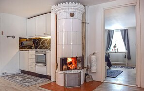 Una cucina compatta con mobili bianchi, un fornello e una stufa a legna.