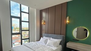 A modern bedroom with a large bed, a view of the city, and a green accent wall. - Luxury Apartment in Colombo (Colombo)