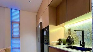 A modern kitchen with wooden cabinets, a built-in oven, and a granite countertop. - Luxury Apartment in Colombo (Colombo)