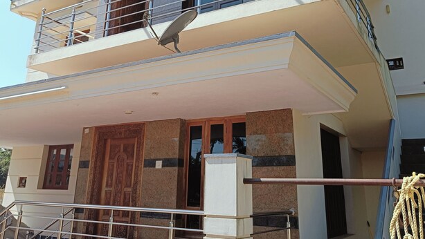 Un immeuble de deux étages doté d’un balcon, d’une antenne parabolique et d’un escalier menant à l’entrée.