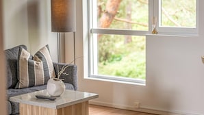 A living room with a grey sofa, a white vase with branches, and a remote control on a wooden coffee table. - Apartment in Myggenäs (54728) (Myggenäs)