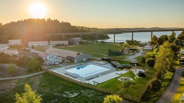 A large building with a swimming pool, surrounded by a grassy area and a forested hill. - Awesome apartment in Myggenäs with swimming pool (Myggenäs)