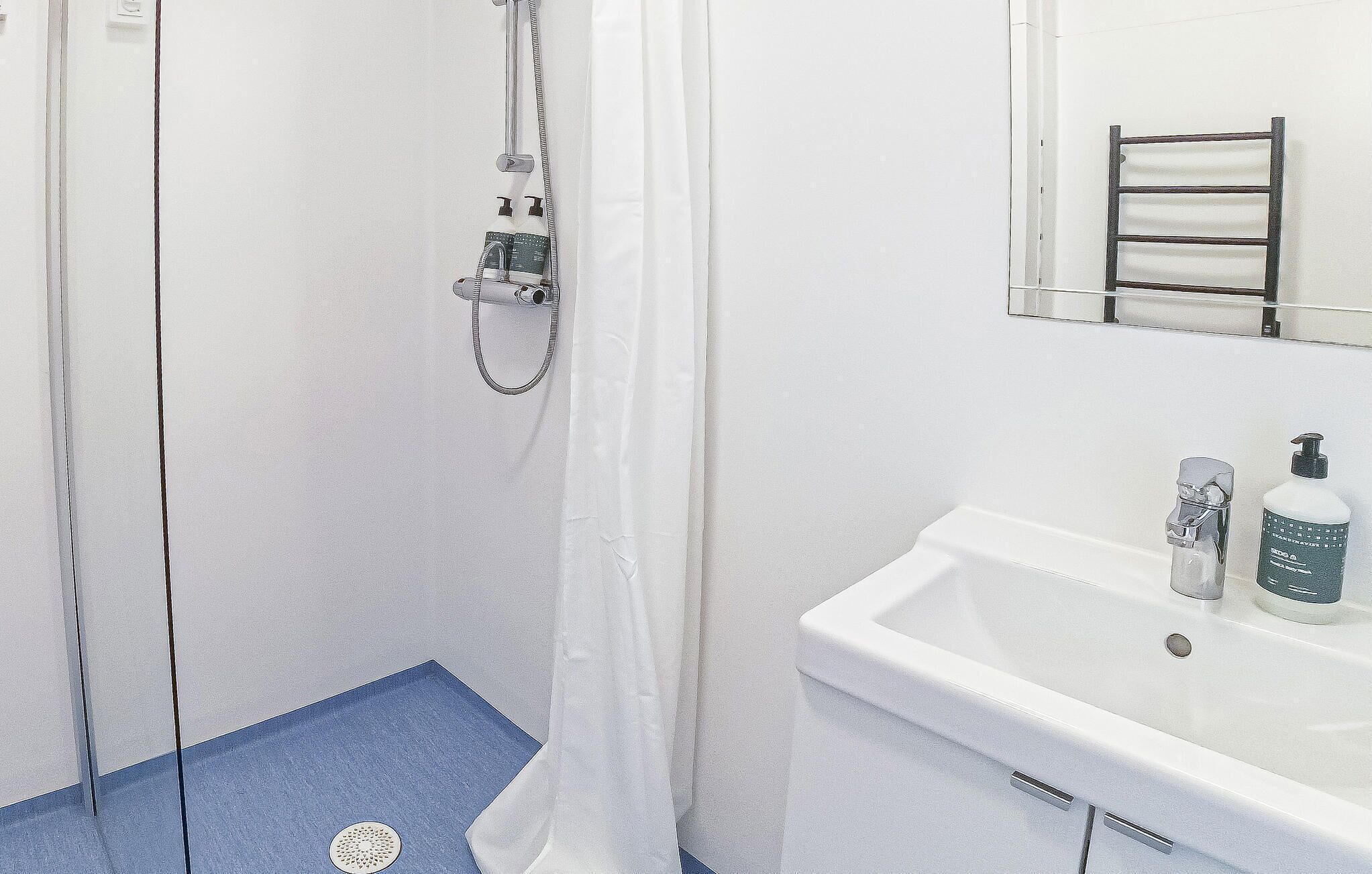 A bathroom with a shower, a sink, and a mirror.