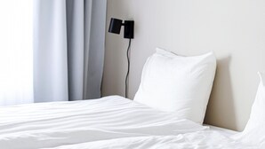 A neatly made bed with white linens in a hotel room.