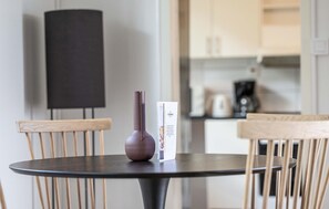 Een ronde tafel met een donker oppervlak, twee houten stoelen, een donkere vaas en een boekje op tafel.