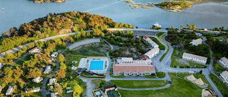 Eine Luftaufnahme eines Küstenresorts mit Schwimmbad, mehreren Gebäuden und einem Straßennetz.
