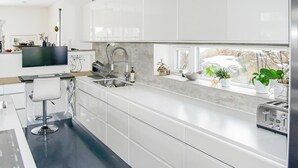 Una cucina moderna con mobili bianchi, un lavello incassato e una finestra vista su un paesaggio innevato.