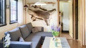 Un saló modern amb un sofà gris, una taula de centre amb un ram de flors i un mural a la paret.