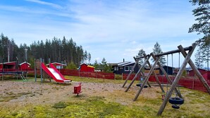 Un parc infantil amb tobogan, cadira de balanceig i cadira de pneumàtic.