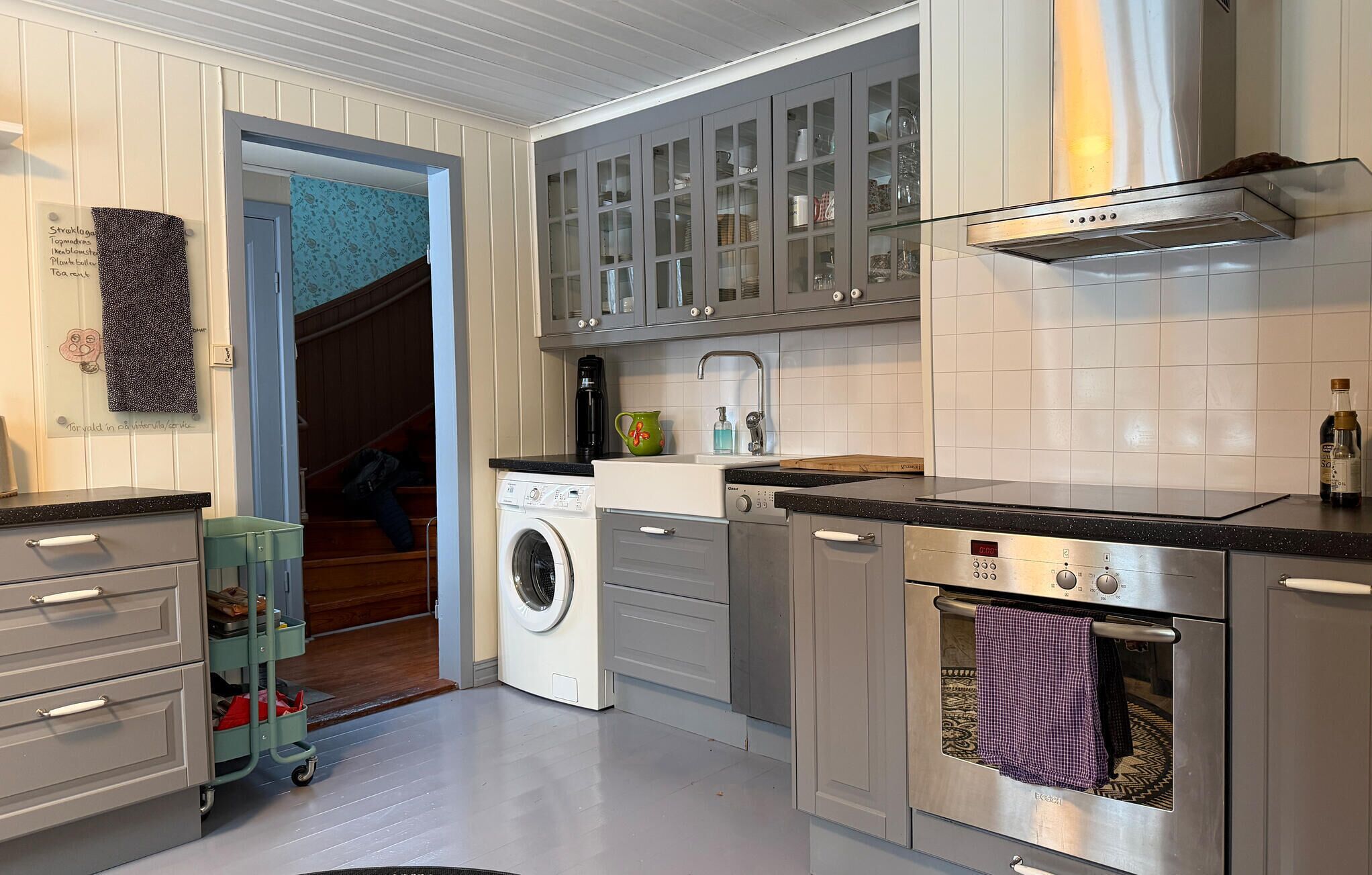 A modern kitchen with stainless steel appliances, a built-in oven, and a washing machine.