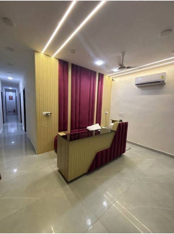 A reception area with a reception desk, a wall-mounted air conditioner, and a hallway leading to other rooms.