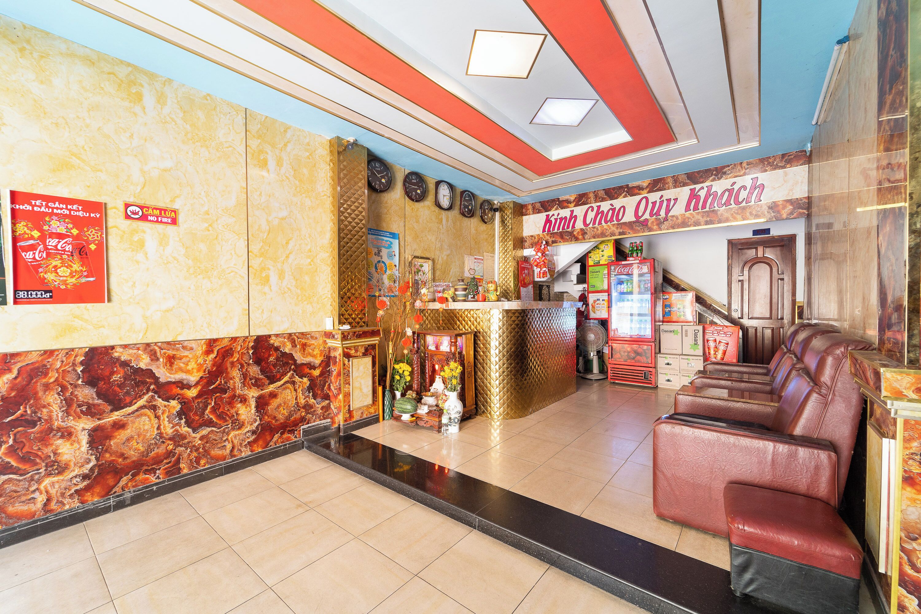 Interior de restaurante con pared de mármol, refrigerador de Coca-Cola y área de estar con sillas de cuero.