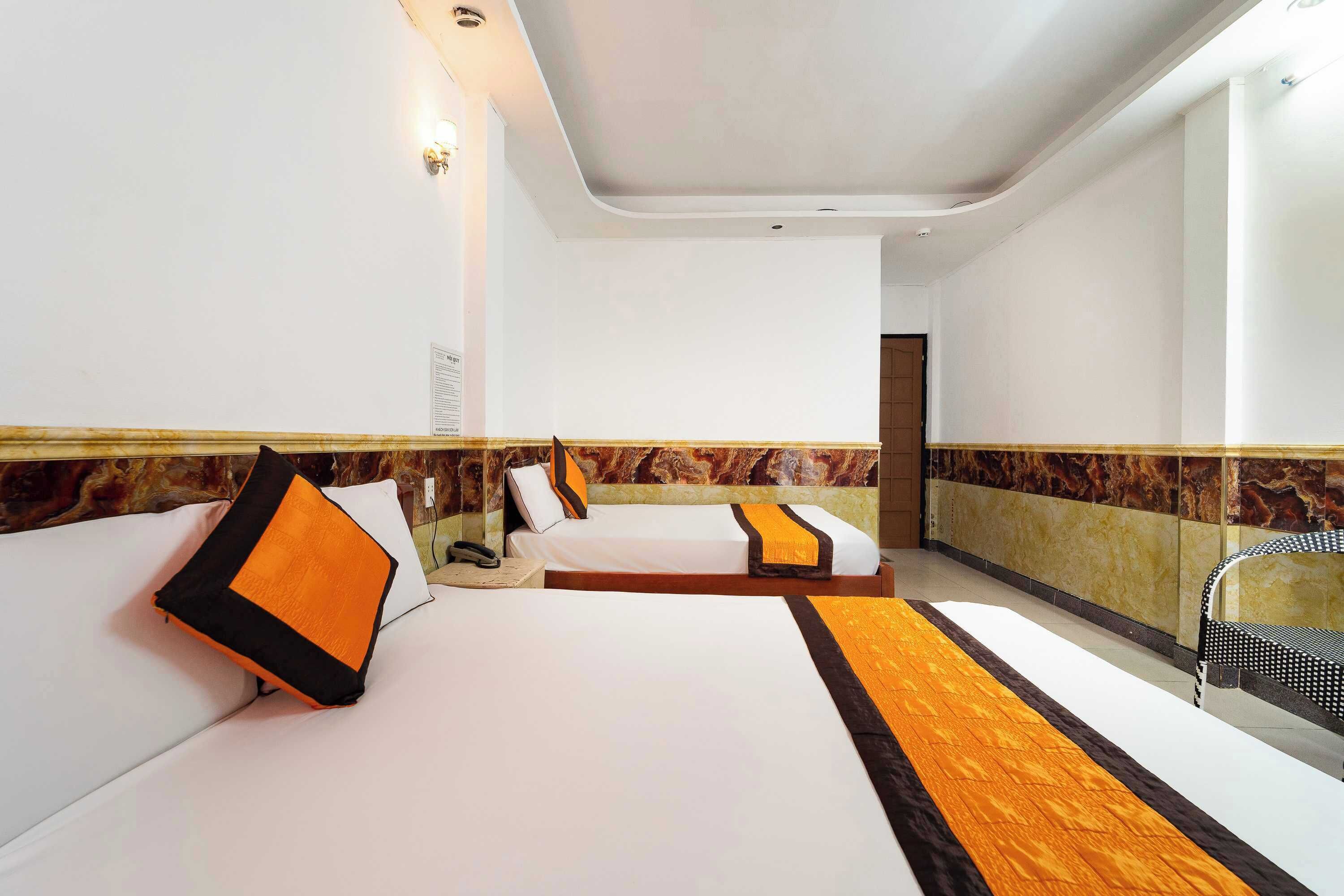 Quarto de hotel com duas camas, parede decorada em mármore e design moderno.