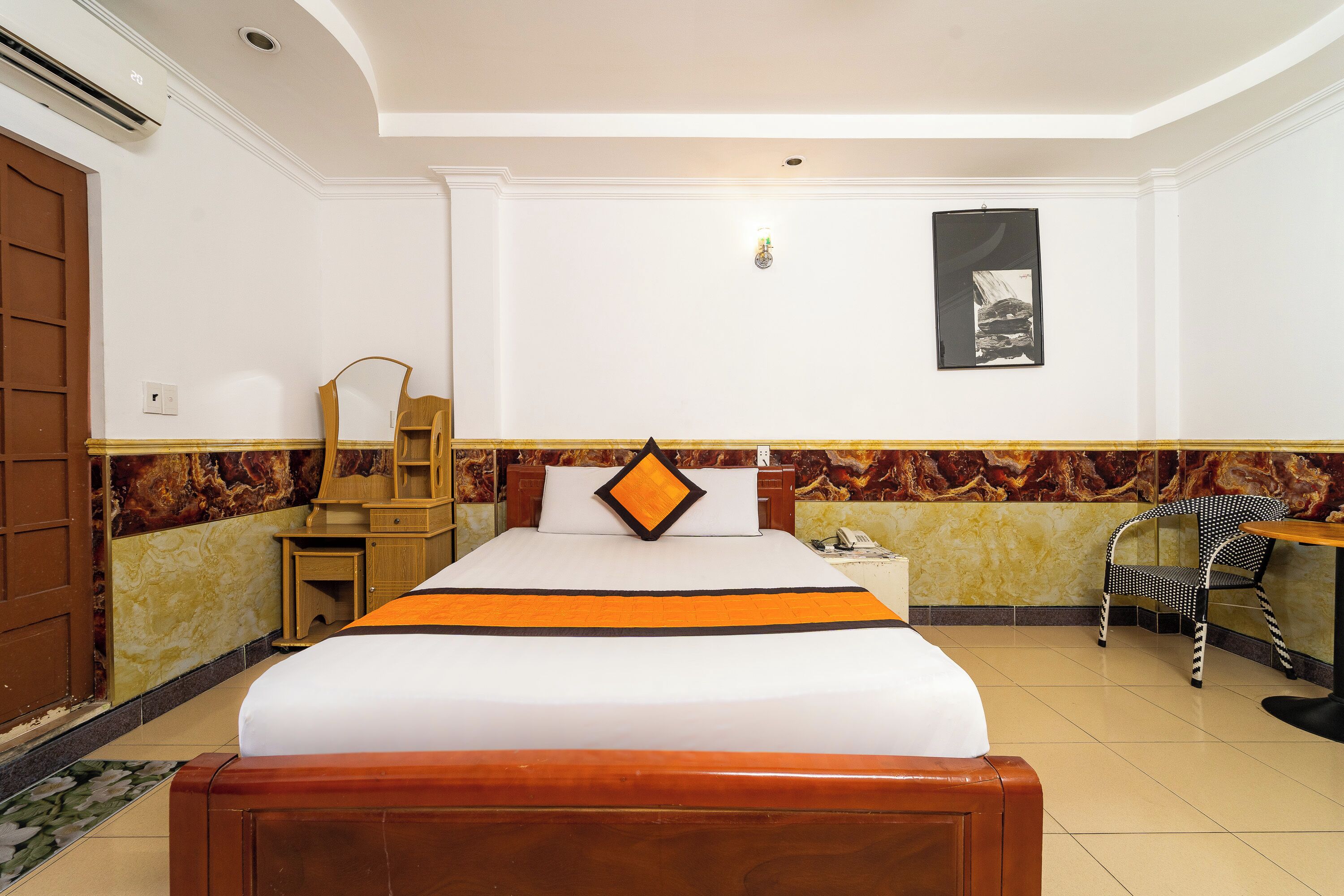 A hotel room with a bed, a desk, a chair, and a wardrobe.