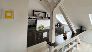 Uma cozinha moderna com armários escuros, estrutura de vigas de madeira e um claraboia.