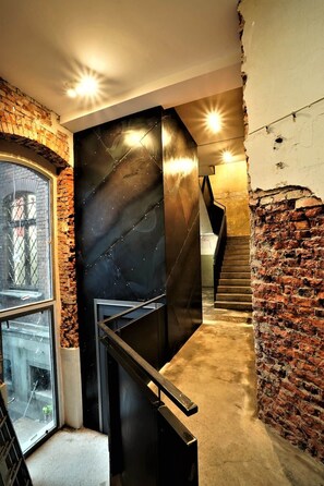 Eine moderne Treppe mit schwarzer Metallgeländer, Ziegelwänden und einem Glasfenster auf der linken Seite.