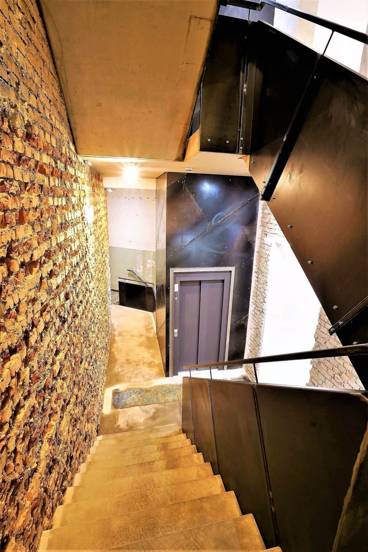 Eine Treppe mit einer Backsteinmauer an einer Seite und Metallgeländern an der anderen, die zu einer Tür oben führt.