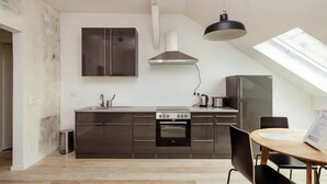 A modern kitchen with a central island, a built-in oven, and a dining area with a round table and chairs. - Central & bright - penthouse 23 in the Häselburg (Gera)