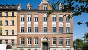 A historic building with a symmetrical facade, large windows, and a central entrance with a decorative arch. - Central & bright - penthouse 23 in the Häselburg (Gera)