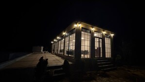 A building with large windows and a flat roof, surrounded by a paved area and some landscaping. - Jalsa Jawai (Bali)