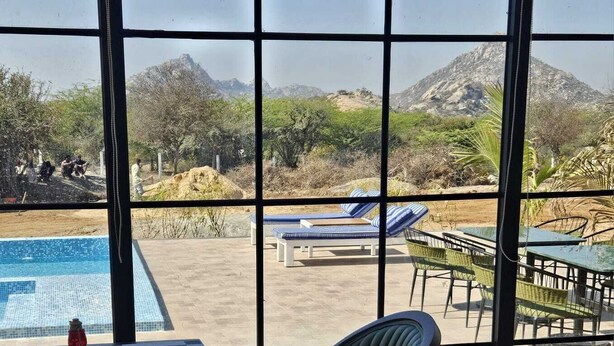 A poolside area with lounge chairs and a table, overlooking a mountainous landscape. - Jalsa Jawai (Bali)