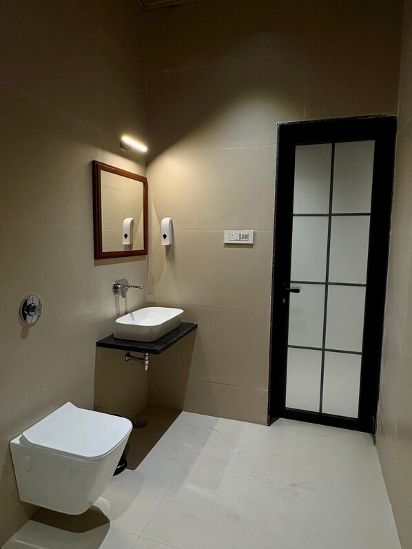 A bathroom with a toilet, sink, mirror, and a door.