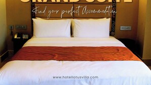 Quarto de hotel com uma cama grande, duas mesas de cabeceira, um criado-mudo e uma luminária fixada na parede. O quarto tem uma paleta de cores quentes e uma cabeceira decorativa.