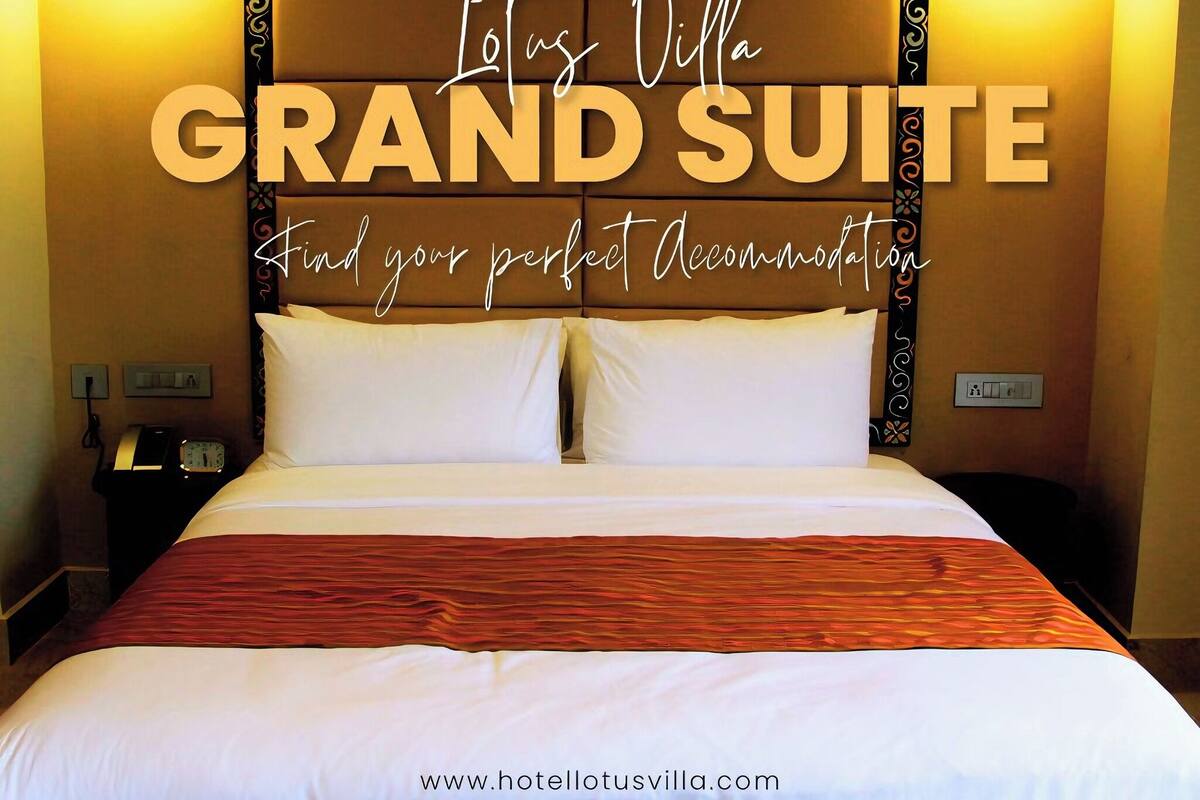 A hotel room with a large bed, two bedside tables, a nightstand, and a wall-mounted light fixture. The room has a warm color scheme and a decorative headboard.