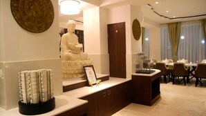 Uma área de recepção com uma estátua de Buda, um certificado emoldurado e um expositor de canetas.