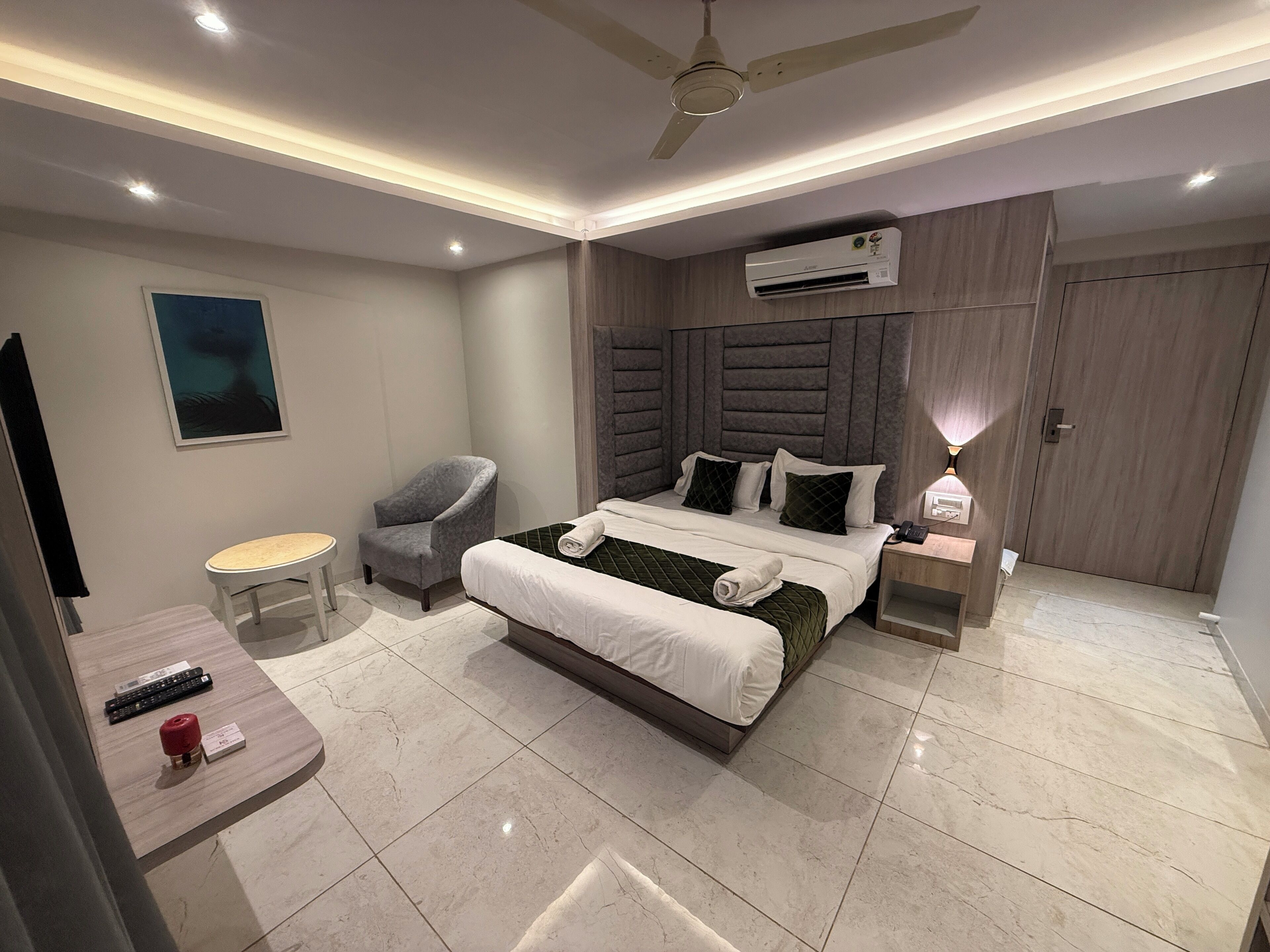 A modern hotel room with a bed, a chair, a desk, and a TV.