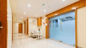 Un couloir d’hôtel avec un comptoir d’accueil, une chaise et une porte en verre avec une pancarte.
