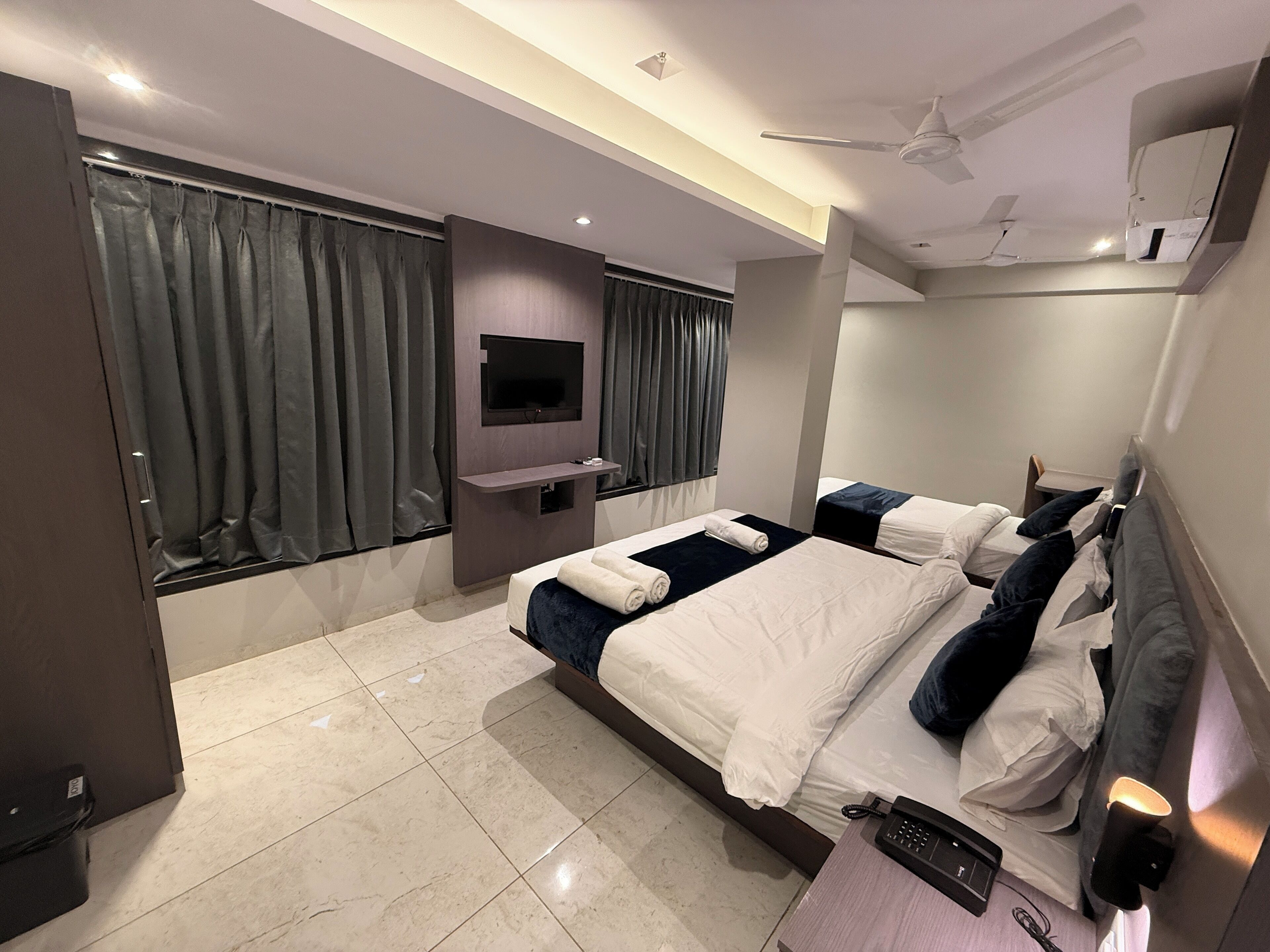 Una camera d'albergo moderna con un letto grande, una TV a schermo piatto montata a parete e una ventola a soffitto.