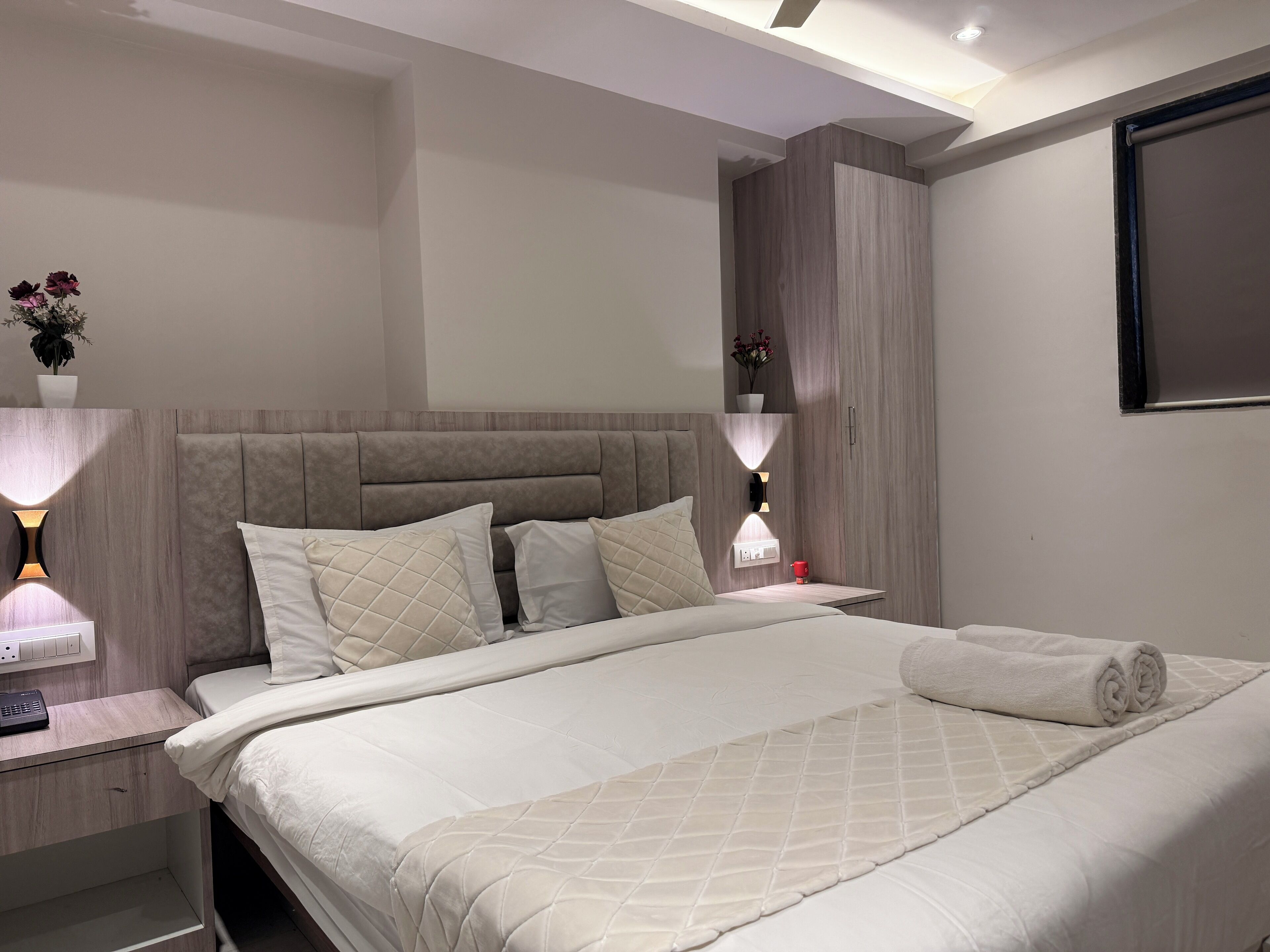 Une chambre moderne avec un grand lit, des lampes de chevet, une table de chevet et un téléviseur fixé au mur.