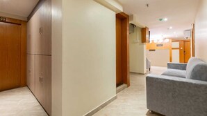 Un espace d’accueil d’hôtel comprenant un comptoir de réception, un espace d’attente avec un canapé et une armoire en bois.
