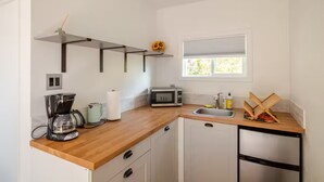 A compact kitchen with a wooden countertop, a coffee maker, a microwave, a sink, and a dishwasher.